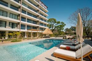 a hotel swimming pool with chaise lounge chairs and an umbrella at Pacific Surfside Ocean Views in Surf City in ChiltiupÃ¡n
