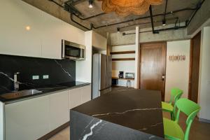 a kitchen with a black counter top and green chairs at Pacific Surfside Ocean Views in Surf City in ChiltiupÃ¡n