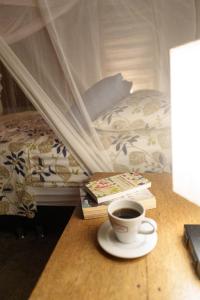 a cup of coffee and books on a table next to a bed at Frana Lodge in El Zaino