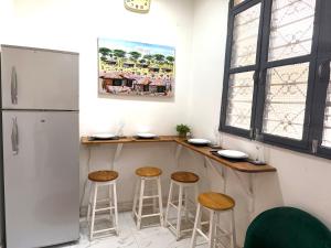 a kitchen with a bar with stools and a refrigerator at The cosy corner in Zanzibar City