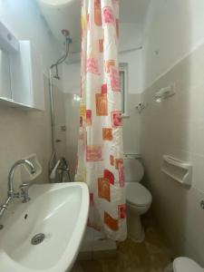 a bathroom with a sink and a toilet and a shower curtain at Apartments MOYRKOS in Missolonghi