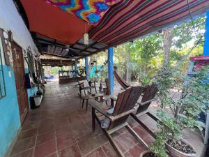 a group of chairs sitting under an umbrella on a porch at Punta Roca Surf House in El Majahual