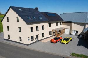 two cars parked in front of a large house at Speedy's Gästehaus in Reimerath