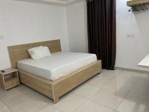 a bedroom with a bed with a wooden frame at Lloyd Hotel and Suites in Benin City