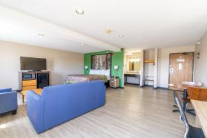 a living room with a blue couch and a bed at Super 8 by Wyndham Sioux City South in Sioux City
