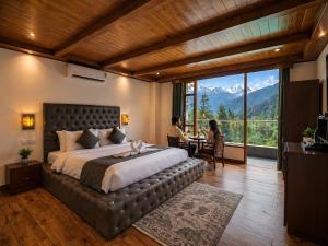 a bedroom with a large bed with a large window at Hotel Asiia Holiday with Swimming Pool -Central Heated and Air Cooled, Near mall road in Kasol