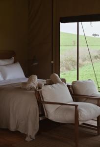 two beds and chairs in a room with a window at Fazenda Azul in Budens