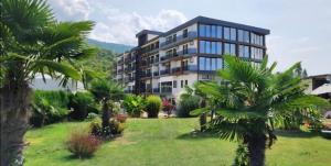 a large building with palm trees in front of it at SANI Apartments by Kanevce in Ohrid