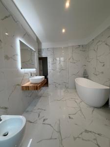 a white bathroom with a sink and a tub and a mirror at Velvet Rooms Florence in Florence