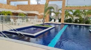 a swimming pool in a resort with chairs and tables at Refúgio Aconchegante & Charmoso! in Aracaju