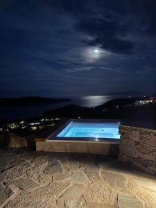 a swimming pool at night with the moon in the sky at To Petrino Serifos in Livadakia