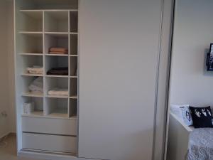a closet with white shelves and a white door at Lenn Rem Eze in Ezeiza +6 photos