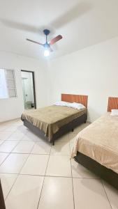 a bedroom with two beds and a ceiling fan at Casa para 9 pessoas a poucos passos do Santuário de Aparecida in Aparecida