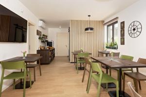 a dining room with wooden tables and green chairs at B&B Plitvice Lacus in Seliste Dreznicko