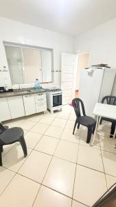 a white kitchen with chairs and a table and a refrigerator at Casa para 9 pessoas a poucos passos do Santuário de Aparecida in Aparecida +21 photos