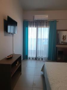 a hotel room with a bed and a television and blue curtains at Buganvilla Sea View apts in Agia Pelagia