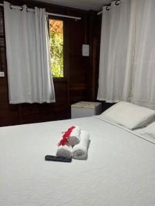 a bed with towels and a remote control on it at Pousada Boldró Home in Fernando de Noronha