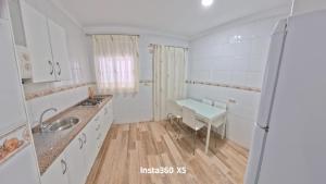a white kitchen with a sink and a table at Apartamentos Bemar in Chipiona