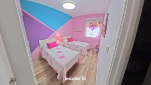 a room with two beds and a purple wall at Apartamentos Bemar in Chipiona