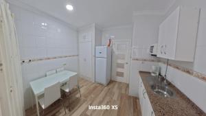 a white kitchen with a sink and a refrigerator at Apartamentos Bemar in Chipiona +17 photos