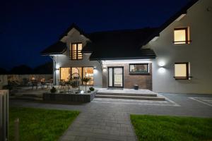 a white house with a patio at night at White House Residence Zator-blisko Energylandii in Zator
