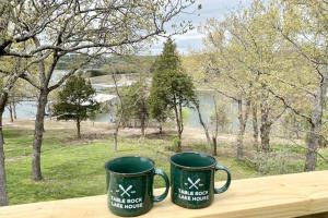 Zwei grüne Kaffeetassen stehen auf einem Holztisch. in der Unterkunft Farmer's Getaway in Reeds Spring
