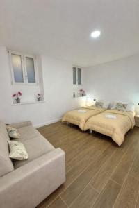 two beds in a white room with a couch at Apt Pisces - Oasi di Menaggio in Menaggio +22 photos