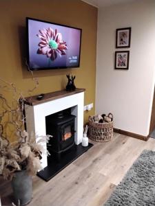 a living room with a fireplace and a flat screen tv at south view farm cottage 1 Bed in Bradford