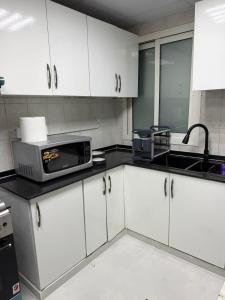 a kitchen with white cabinets and a microwave at High-floor Luxury Apartment! in Ajman 