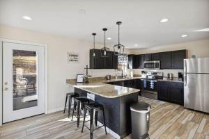 a kitchen with black cabinets and a kitchen island with bar stools at Spacious 4 bd with hottub, theater & game zone in Union Grove +39 photos