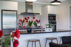 a kitchen with a counter with three stools in it at Spacious One-Bedroom with Private Bathroom Aotea in Porirua