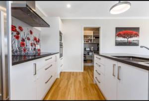 a kitchen with white cabinets and a red tree painting on the wall at Spacious One-Bedroom with Private Bathroom Aotea in Porirua +3 photos