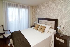 a bedroom with a large white bed with a window at CANELAS CLASS con AMPLIAS TERRAZAS in Portonovo
