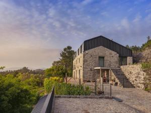 a stone house on a hill with a black roof at Quinta Cerca da Milhera in Ponte da Barca