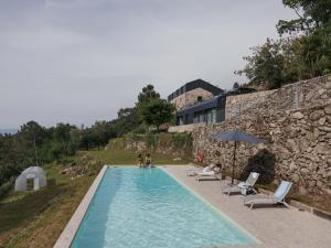 a swimming pool with chairs and people sitting around it at Quinta Cerca da Milhera in Ponte da Barca