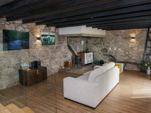 a living room with two white couches and a stone wall at Quinta Cerca da Milhera in Ponte da Barca