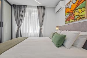 a bedroom with a bed with white sheets and green pillows at Athens Theatrou Apartments in Athens