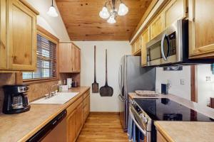 a kitchen with wooden cabinets and a stainless steel refrigerator at Woodland in Branson West +30 photos