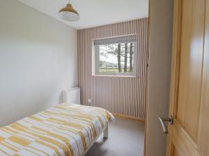 a bedroom with a bed and a window at Redwood in Harlech