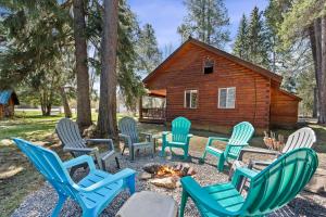 a group of chairs around a fire in front of a cabin at Glacier Cabins in Martin City