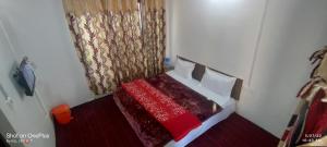 a small bedroom with a bed with a red bedspread at New Heaven Rose in Pahalgām