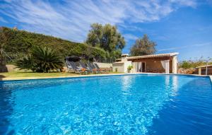 a blue swimming pool with chairs and a house at Ca Na Rosa De Selva in El Port de la Selva