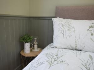 a bed with a white comforter and a table with a night stand with at 1 Bed in Hawarden oc-93595 in Hawarden