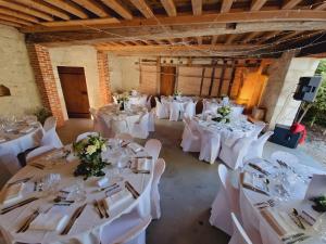 a room with white tables and chairs with flowers on them at Gîte De Charme - La Mésangerie in Saint-Satur