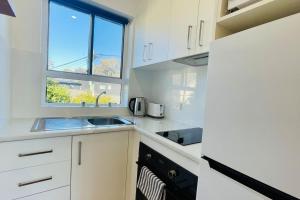 a white kitchen with a sink and a window at The Newton in Lyons