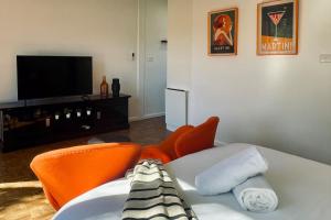 a living room with orange chairs and a flat screen tv at The Newton in Lyons