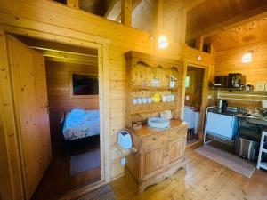 a room with a kitchen and a bedroom in a cabin at Garden Cabin at Shengan in Banavie