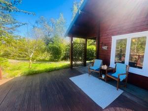 a porch of a house with two chairs and a table at Garden Cabin at Shengan in Banavie