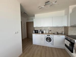 a kitchen with white cabinets and a washing machine at Kabakum See infinity in Varna City