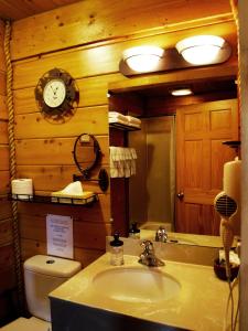 a bathroom with a sink and a toilet and a clock at Alaskan Suites in Homer